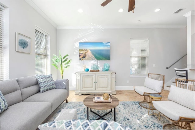 living room with ornamental molding, visible vents, baseboards, and a ceiling fan