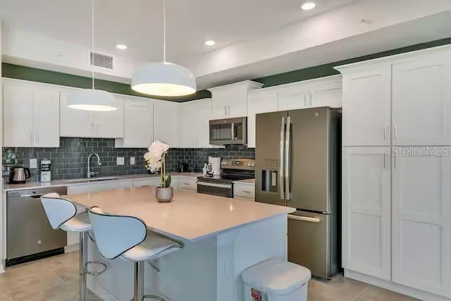 kitchen with white cabinetry, appliances with stainless steel finishes, and hanging light fixtures