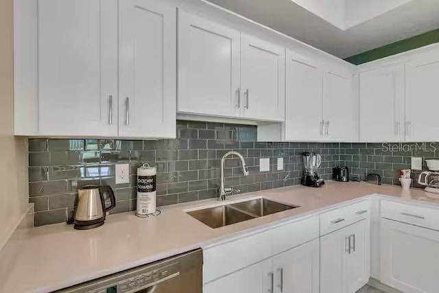 kitchen featuring decorative backsplash, sink, white cabinetry, and stainless steel dishwasher