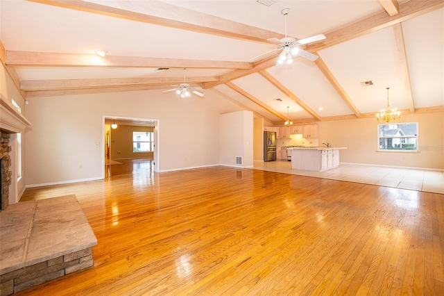 unfurnished living room with a fireplace, ceiling fan with notable chandelier, and light hardwood / wood-style flooring