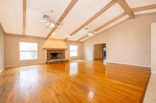 unfurnished living room with beamed ceiling, ceiling fan, a fireplace, and light hardwood / wood-style floors