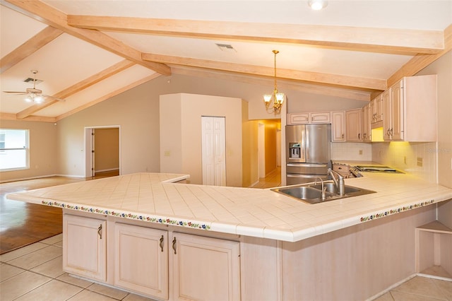 kitchen with pendant lighting, sink, backsplash, stainless steel refrigerator with ice dispenser, and lofted ceiling with beams