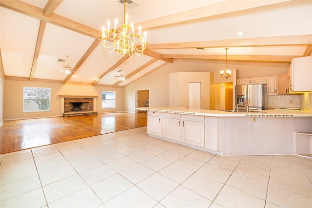 kitchen with tasteful backsplash, stainless steel fridge with ice dispenser, decorative light fixtures, and plenty of natural light