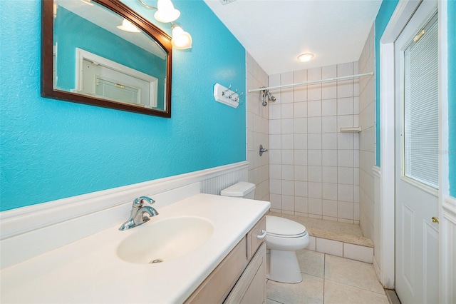 bathroom with vanity, toilet, tile patterned flooring, and a tile shower