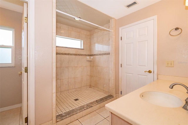 bathroom with tile patterned flooring, vanity, and tiled shower