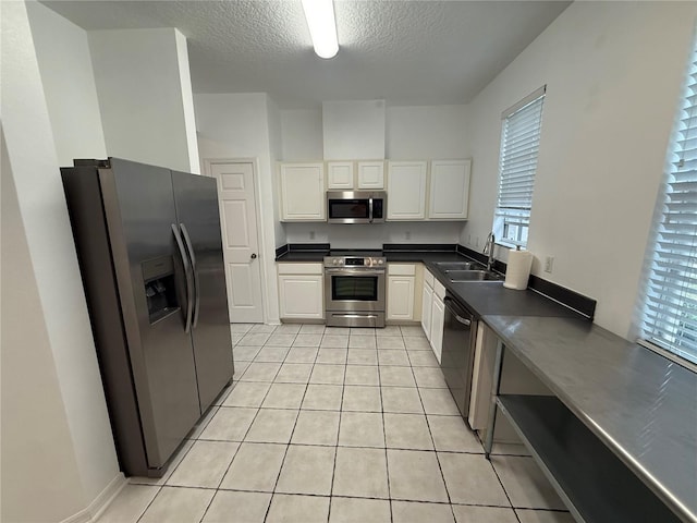 kitchen with sink, light tile patterned floors, stainless steel appliances, and white cabinets