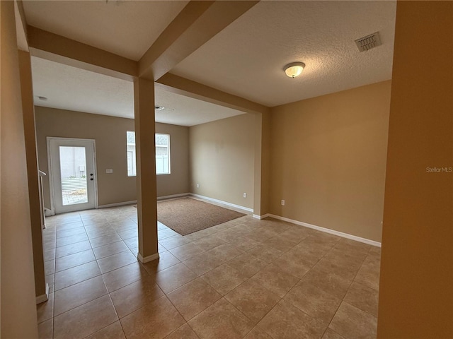 tiled empty room with a textured ceiling