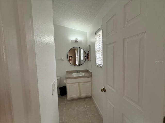 bathroom with vanity, toilet, tile patterned flooring, and a textured ceiling