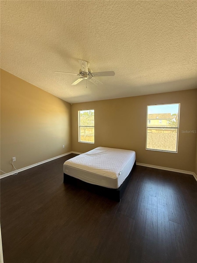 unfurnished bedroom featuring a textured ceiling, dark wood-type flooring, and ceiling fan