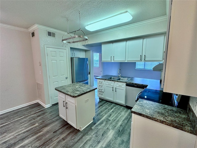 kitchen with sink, appliances with stainless steel finishes, white cabinetry, a textured ceiling, and a kitchen island