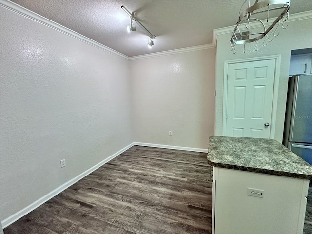 unfurnished dining area featuring crown molding, track lighting, dark hardwood / wood-style floors, and a textured ceiling