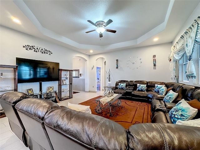 living room featuring a tray ceiling and ceiling fan