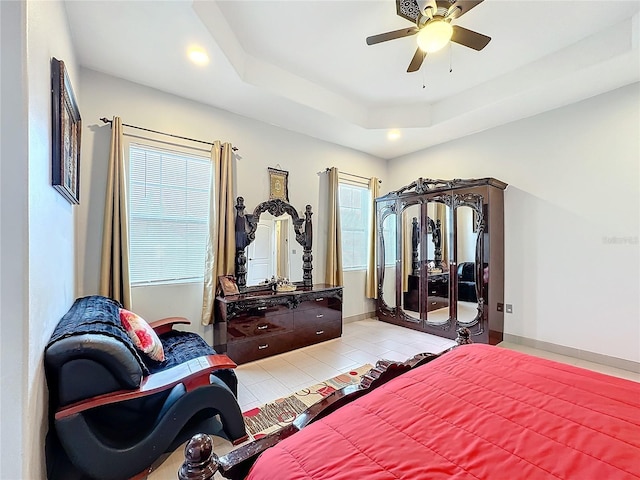 tiled bedroom with a tray ceiling and ceiling fan