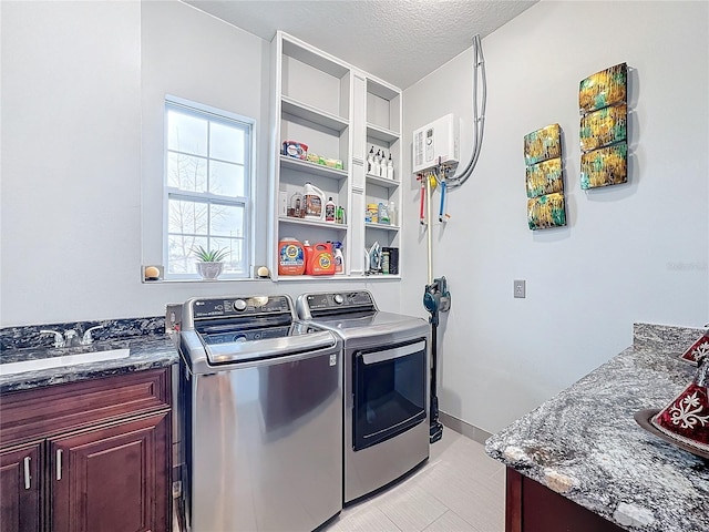 laundry area with sink, washing machine and clothes dryer, cabinets, and a textured ceiling