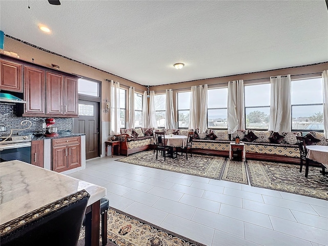 interior space featuring stainless steel range with electric stovetop, light tile patterned floors, a textured ceiling, and backsplash