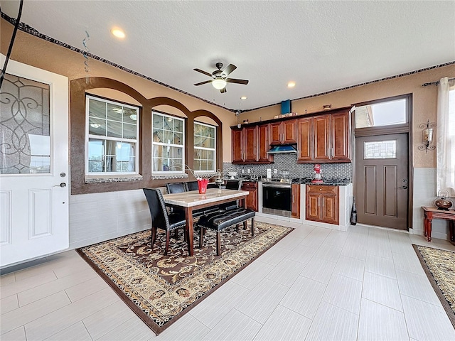 kitchen featuring backsplash, stainless steel stove, a textured ceiling, and ceiling fan