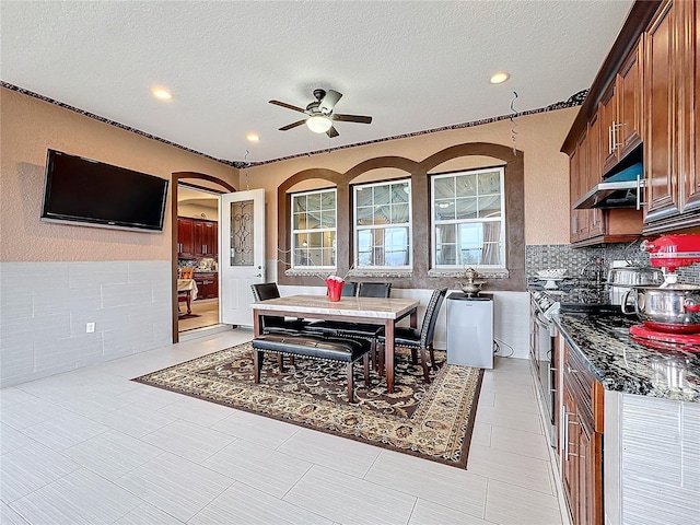 kitchen featuring ceiling fan, backsplash, a textured ceiling, and dark stone counters