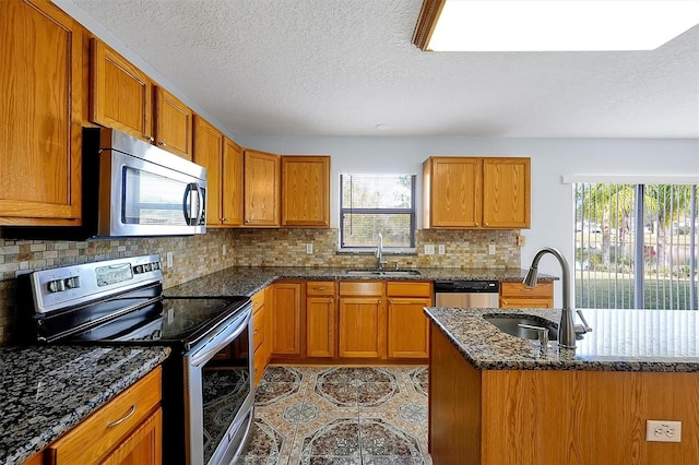 kitchen featuring dark stone countertops, sink, plenty of natural light, and stainless steel appliances