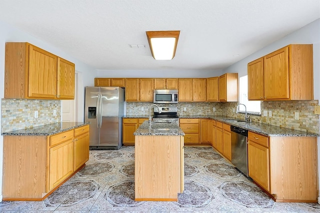 kitchen with tasteful backsplash, sink, stainless steel appliances, and an island with sink