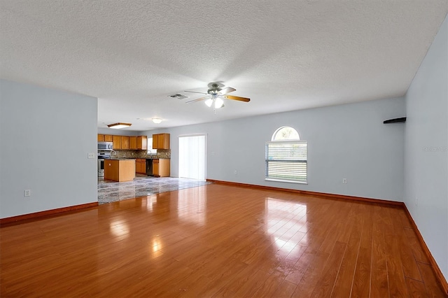 unfurnished living room featuring a textured ceiling, ceiling fan, and light hardwood / wood-style flooring