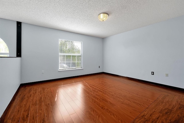 unfurnished room featuring wood-type flooring and a textured ceiling