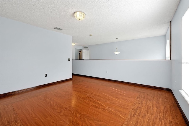 empty room with hardwood / wood-style flooring and a textured ceiling