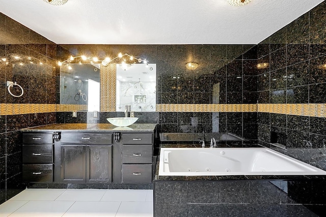 bathroom featuring tile walls, vanity, a relaxing tiled tub, tile patterned floors, and a textured ceiling