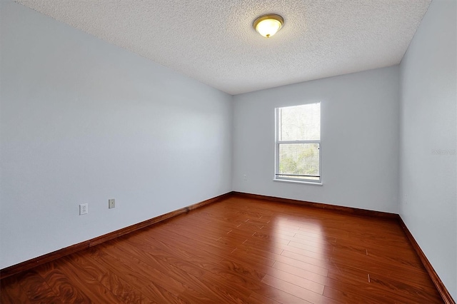 empty room with wood-type flooring and a textured ceiling