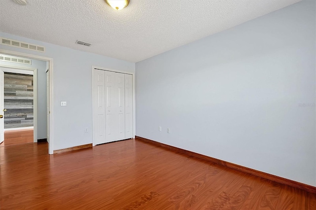 unfurnished bedroom with dark wood-type flooring, a closet, and a textured ceiling