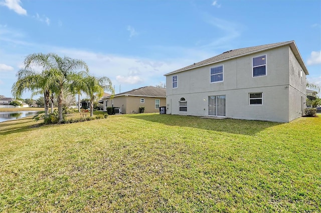 back of property featuring a water view and a lawn