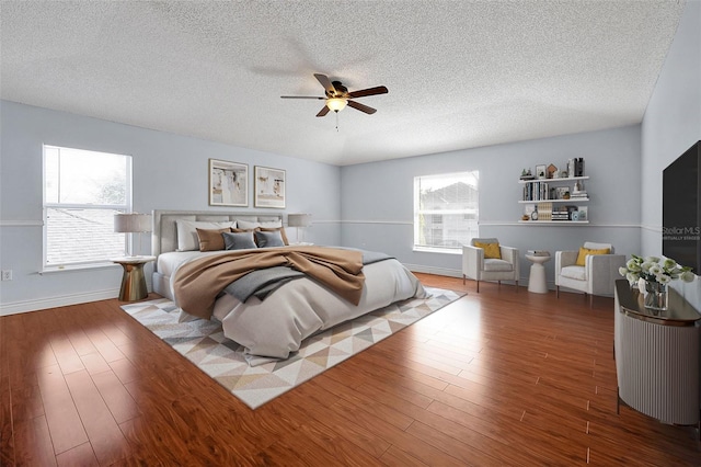 bedroom featuring dark hardwood / wood-style flooring, ceiling fan, multiple windows, and a textured ceiling