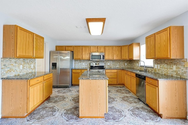 1633 Corner Meadow Cir, Orlando, FL 32820 - kitchen featuring appliances with stainless steel finishes, a sink, dark stone counters, an island with sink, and tasteful backsplash