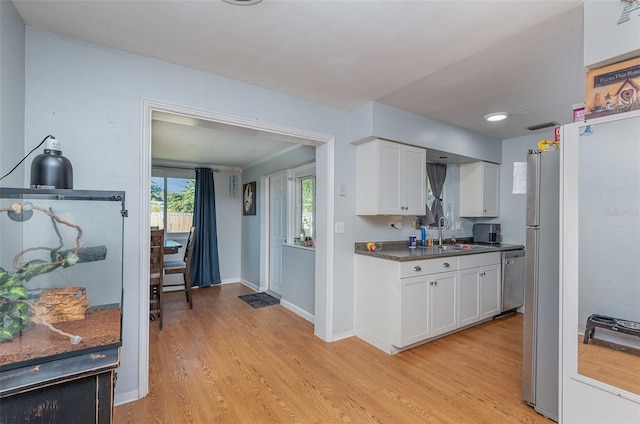 kitchen featuring stainless steel appliances, white cabinetry, sink, and light hardwood / wood-style flooring