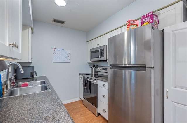 kitchen featuring stainless steel appliances, sink, white cabinets, and light hardwood / wood-style floors