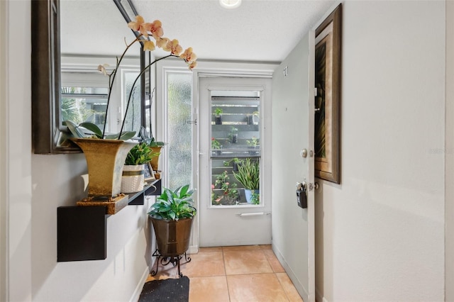 doorway to outside featuring light tile patterned floors and a textured ceiling