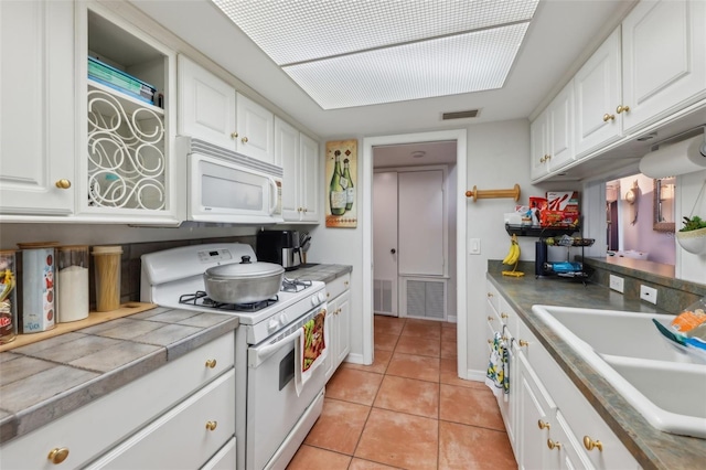 kitchen featuring light tile patterned flooring, white appliances, sink, and white cabinets