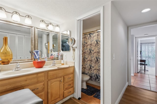 bathroom with curtained shower, hardwood / wood-style flooring, vanity, toilet, and a textured ceiling