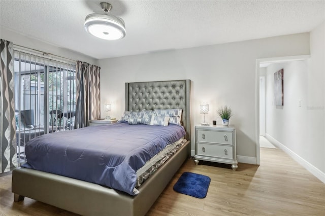 bedroom featuring a textured ceiling and light hardwood / wood-style flooring