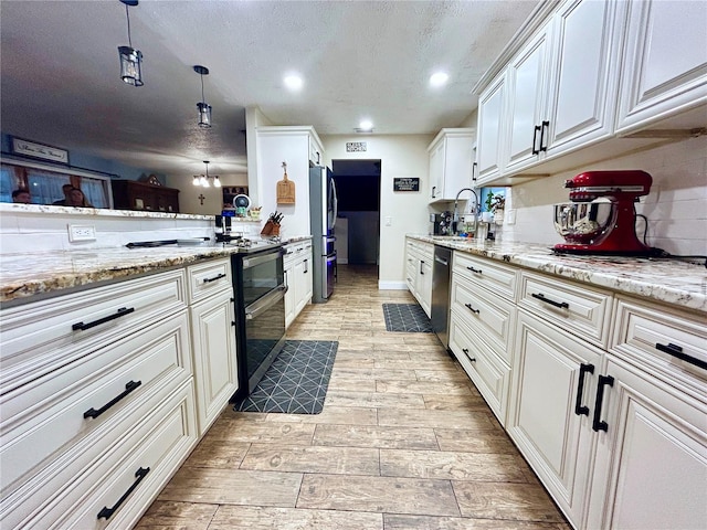 kitchen featuring pendant lighting, sink, stainless steel appliances, light stone countertops, and white cabinets