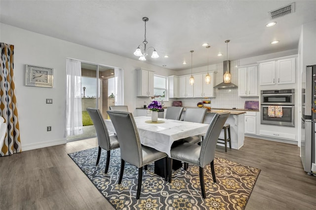 dining space with hardwood / wood-style flooring and a notable chandelier