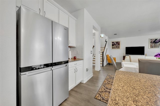 kitchen featuring white cabinetry, tasteful backsplash, stainless steel refrigerator, and light wood-type flooring