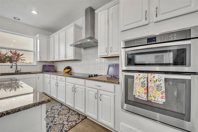 kitchen with white cabinetry, sink, and wall chimney exhaust hood