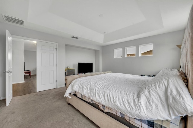 carpeted bedroom with a tray ceiling