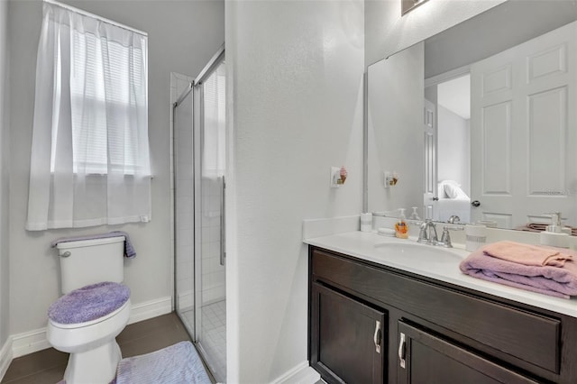 bathroom with a shower with door, vanity, tile patterned flooring, and toilet