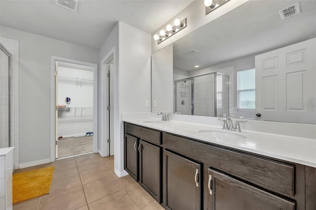 bathroom with tile patterned flooring, vanity, and walk in shower