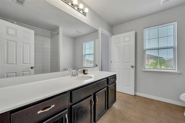 bathroom with tile patterned floors, toilet, vanity, and a shower