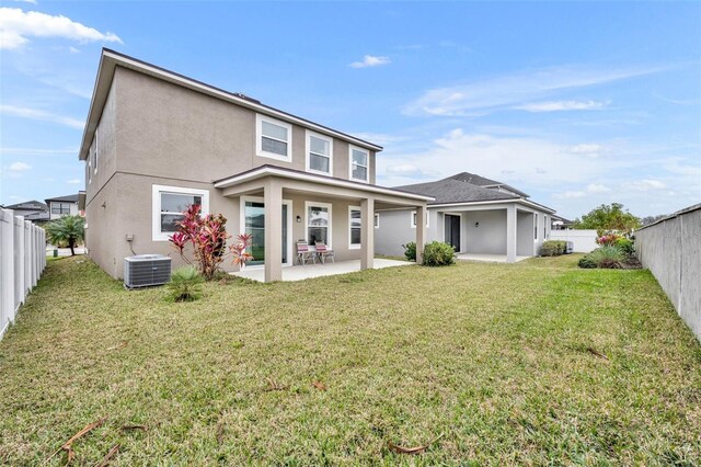 rear view of house with cooling unit, a patio, and a lawn