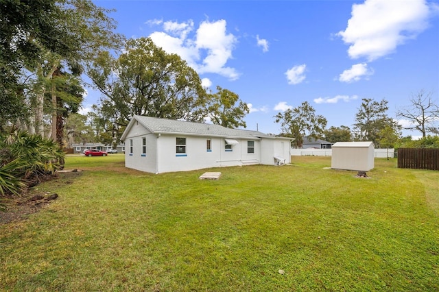 rear view of property featuring a lawn and a storage shed