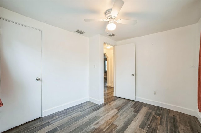 unfurnished bedroom with ceiling fan, dark hardwood / wood-style floors, and a closet