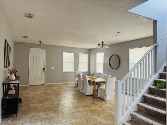 dining space with a healthy amount of sunlight, a chandelier, and a textured ceiling